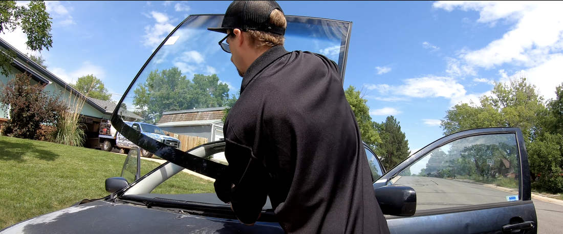 Auto glass technician holding a windshield to replace the old one
